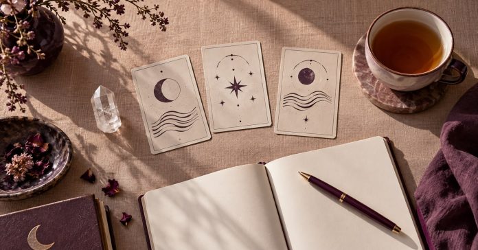 A journal, abstract symbolic cards and a clear quartz point arranged for a reflective reading.