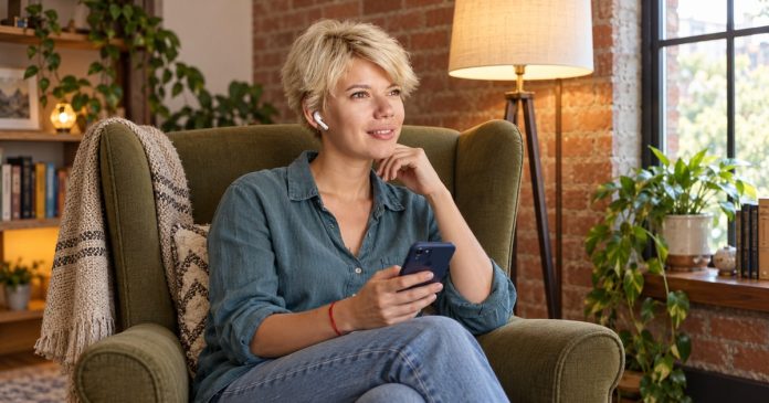 ex-return-distinct-model-20261014 A client listening to a telephone reading through a wireless earbud while holding her phone.